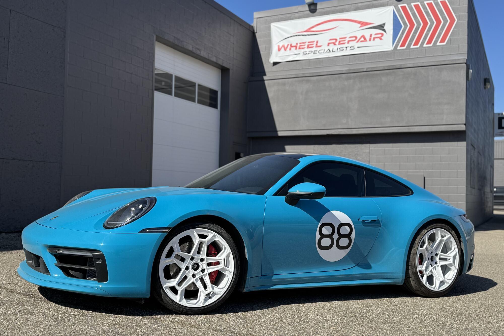 Blue Porsche 911 with white refinished wheels