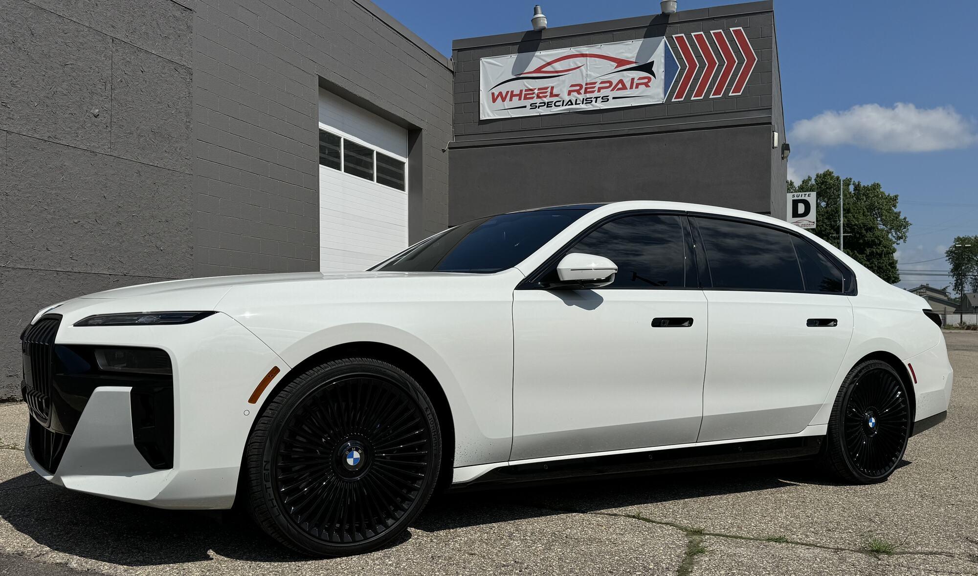 White BMW 7 Series with custom black wheels
